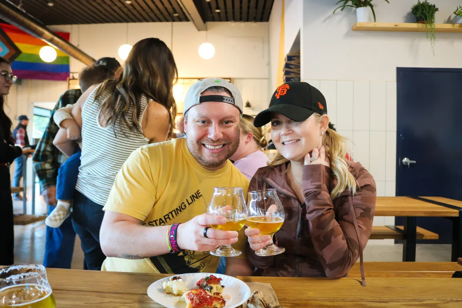 A couple smiling and drinking beer at the Barebottle Walnut Creek taproom.